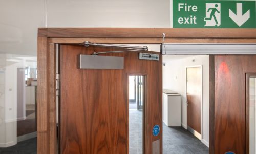 A pair of internal fire rated doors with a close up of the door closer and the surface mounted maglock.