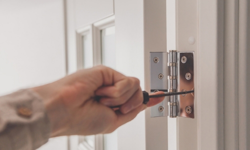 Hinge being adjusted with a screwdriver on a door