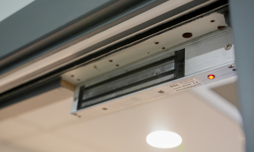 Face of a maglock body, mounted to a door frame.