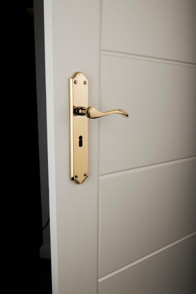 Brass door handle with keyhole on white door